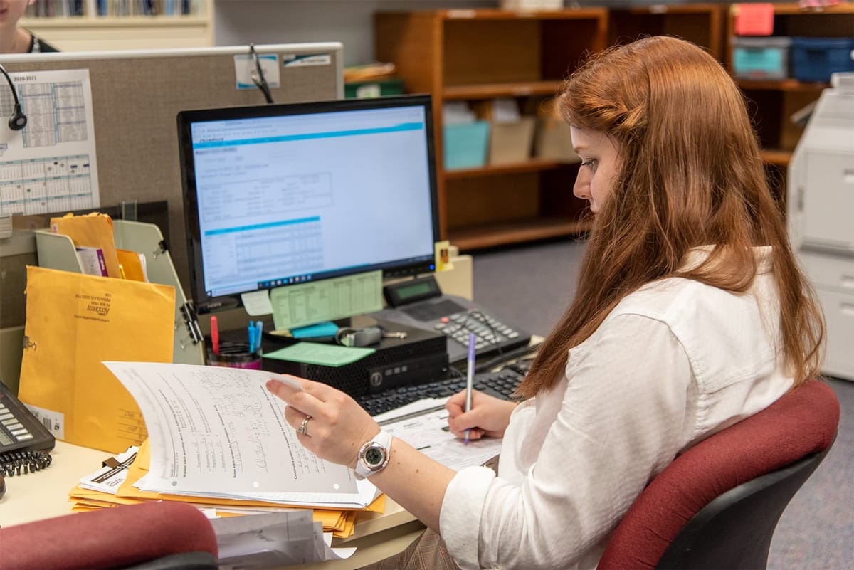 PCC Student female sitting at a desk and grading in ab Abeka office