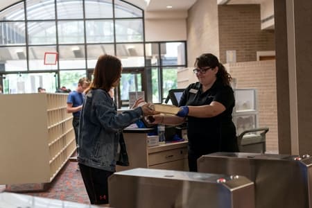 Student on campus being handing a dining hall take out box.