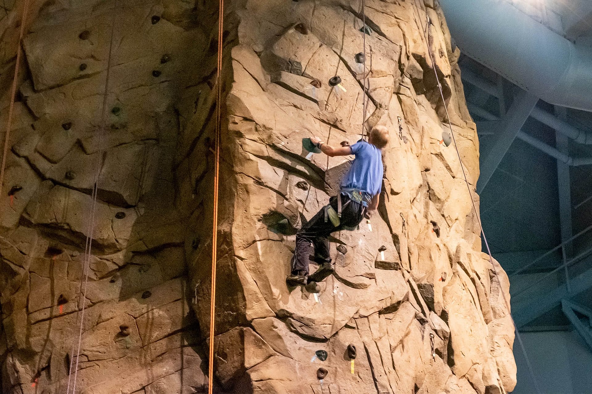 Male student climbing the Sports Center rock wall.