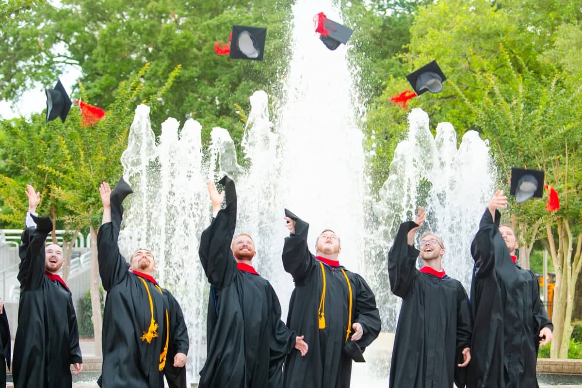 2024 Graduate guys toss their hat up after Commencement