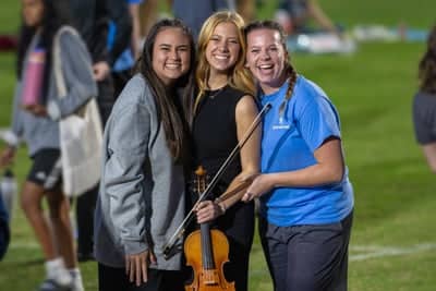 PCC girls pose with a violinist at Concert on the Green. 