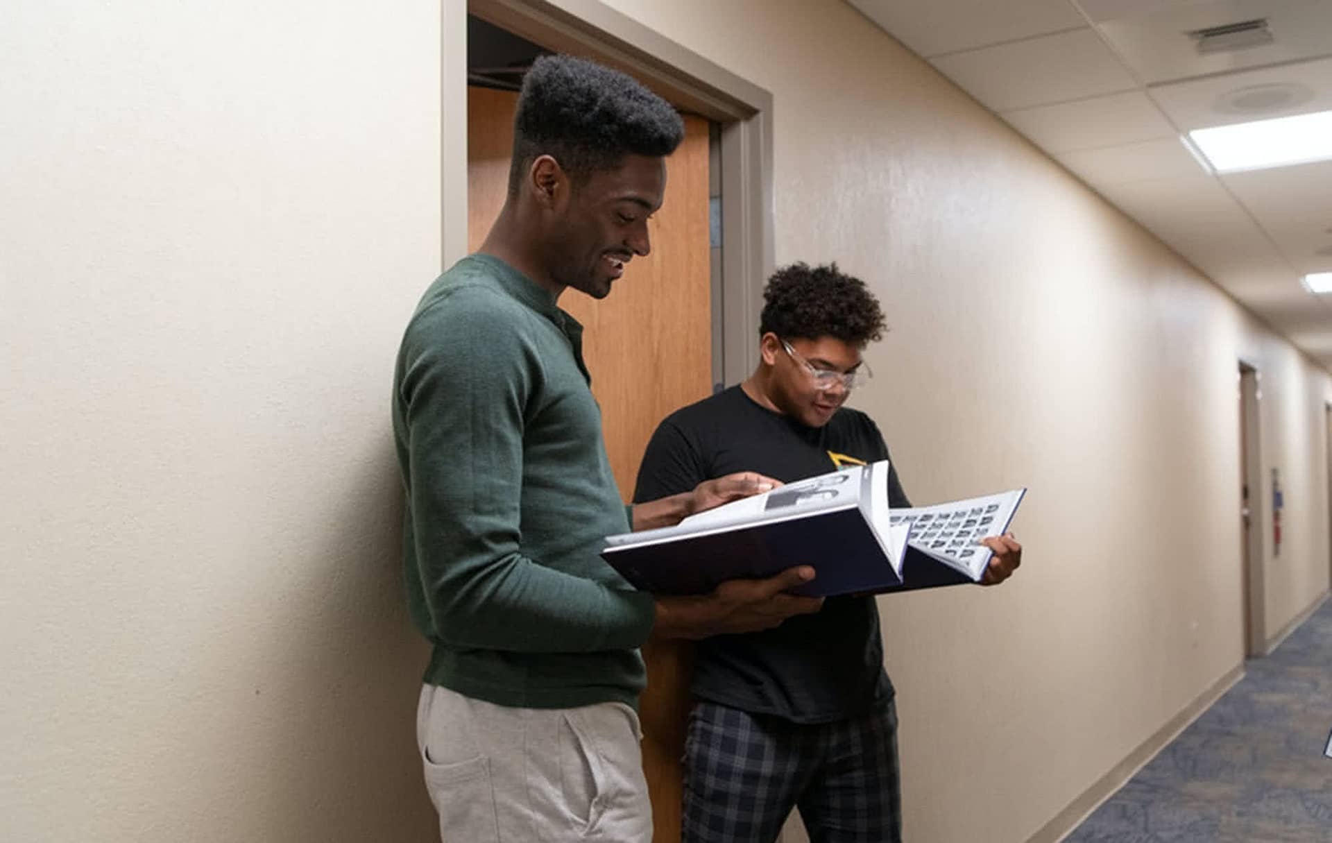 Two male PCC students looking at Summit Yearbooks.