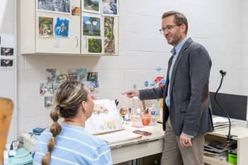 Mr. Greg Hewitt helping a graduate student with her artwork