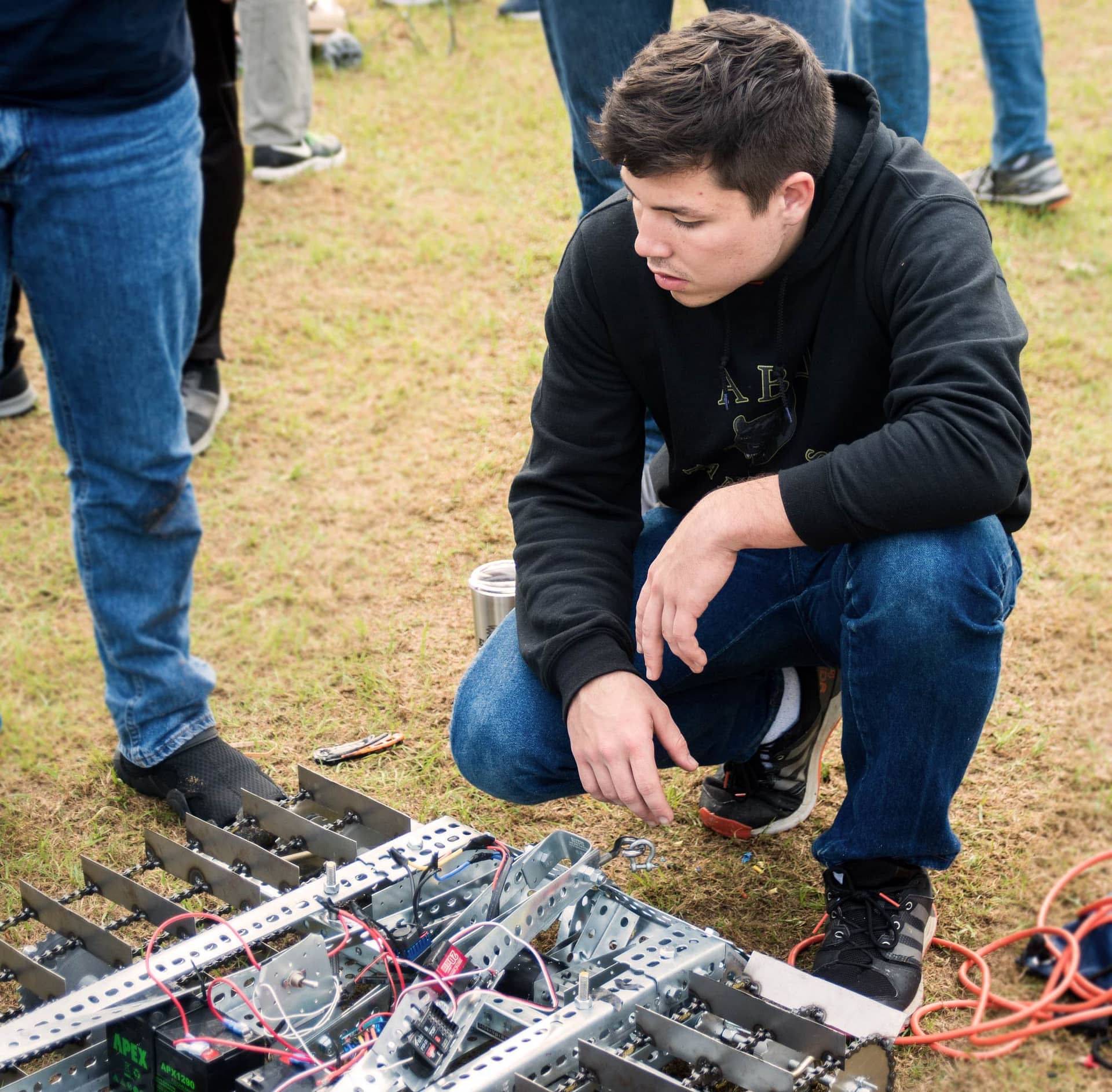 Male student looking at his team's robot for the Engineering Design Contest.