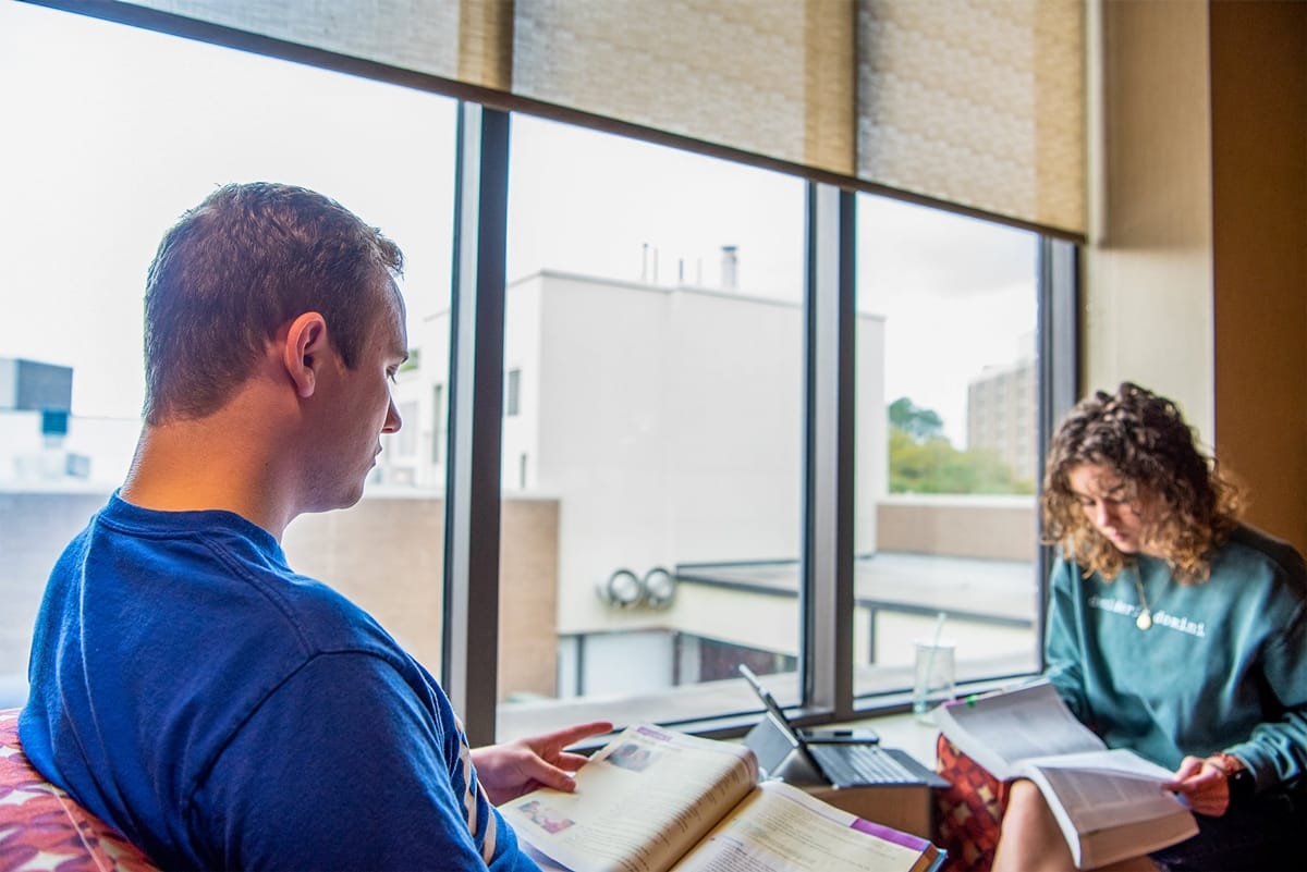 PCC Male and Female studying by a window in the commons
