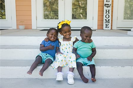 Children sitting on the porch of one of the campus' cottages