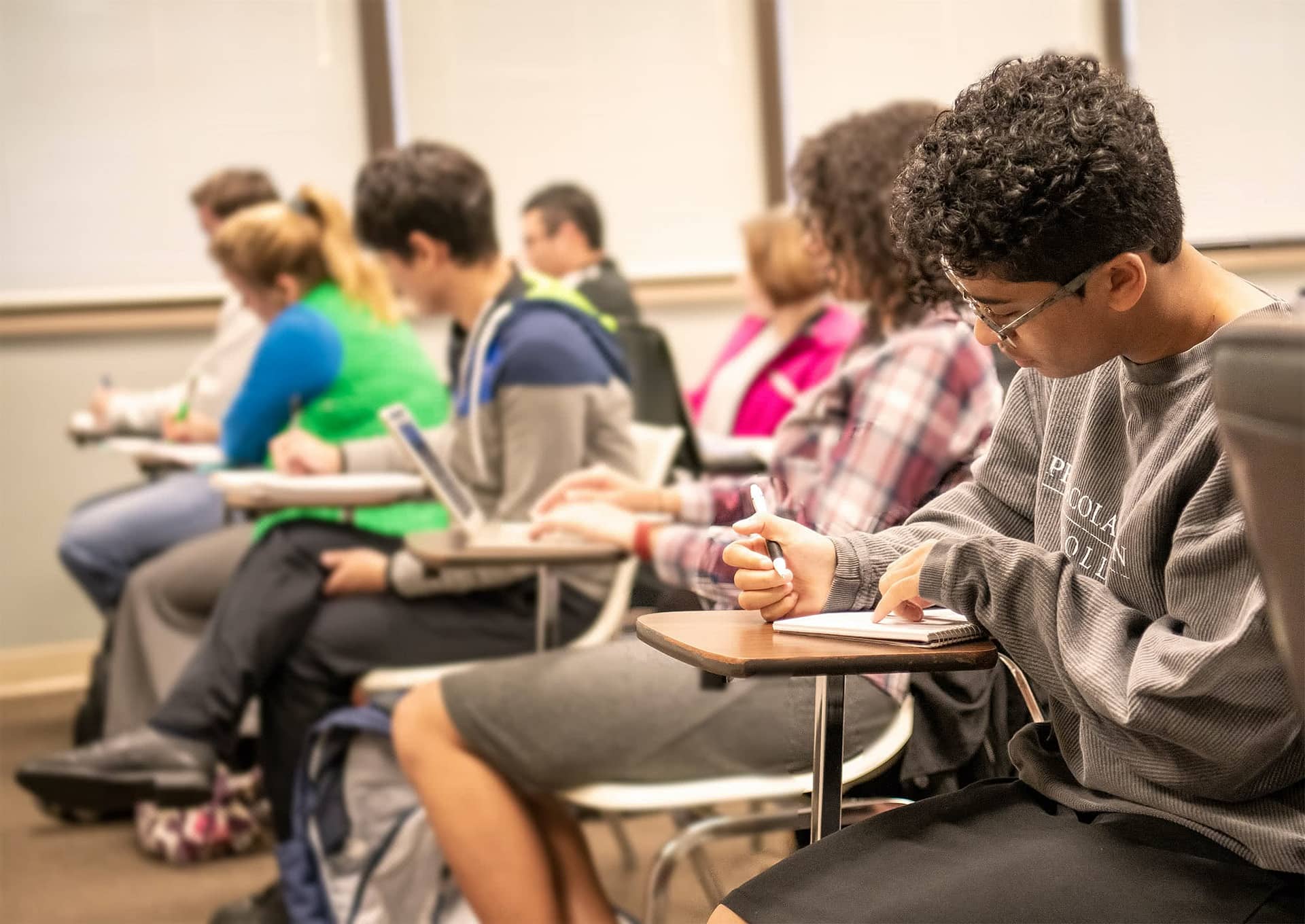 Interterm students sitting at desks and taking notes.