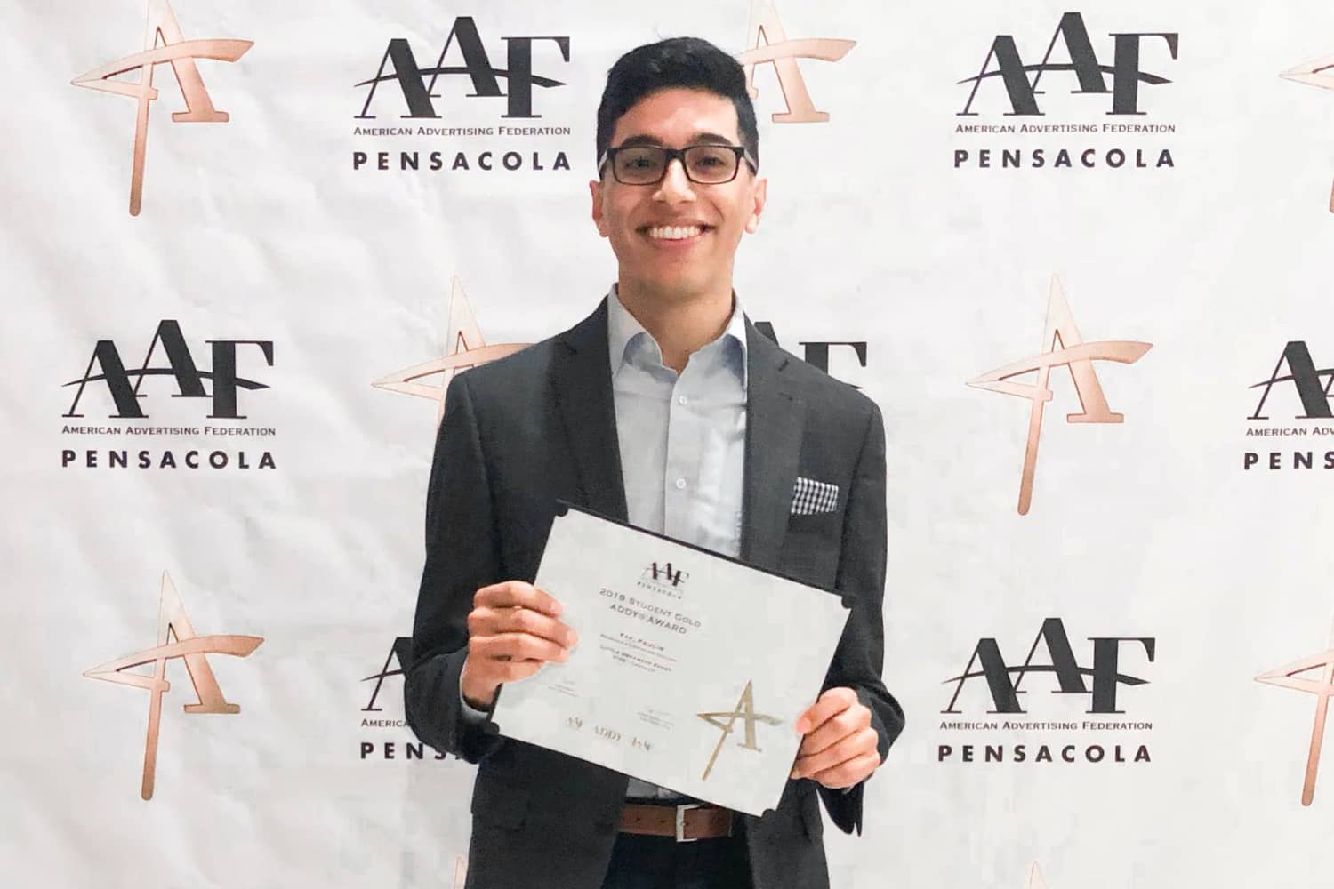 A male student poses with his award