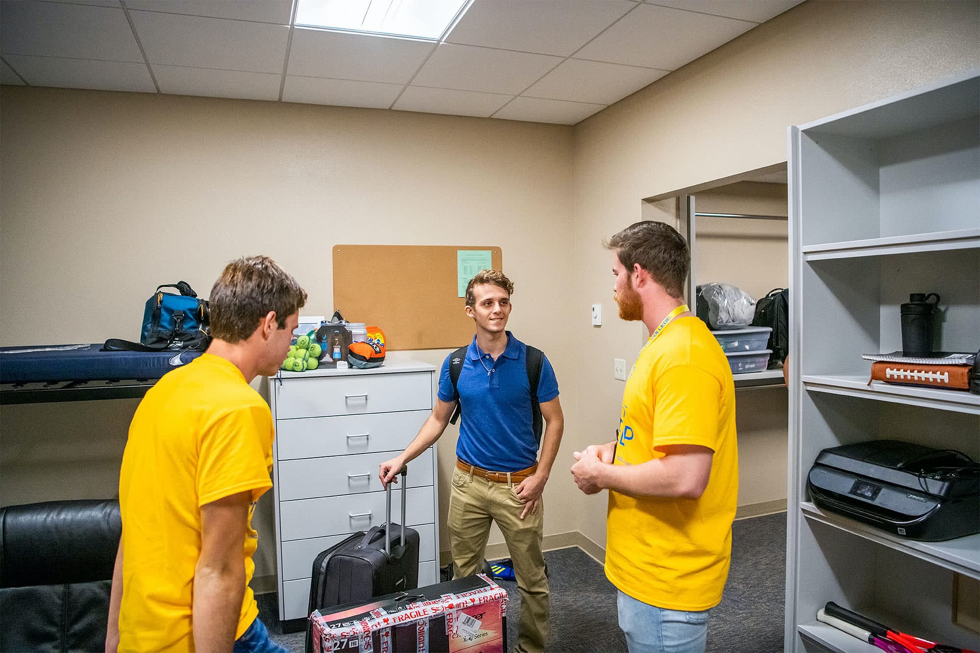 Two greeters elp a new student move into his room