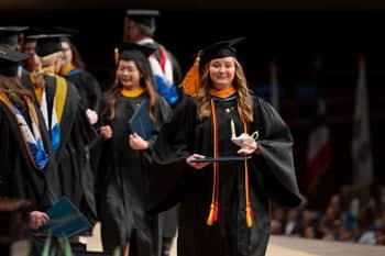 2024 Nursing Graduate walks across the stage during Commencement