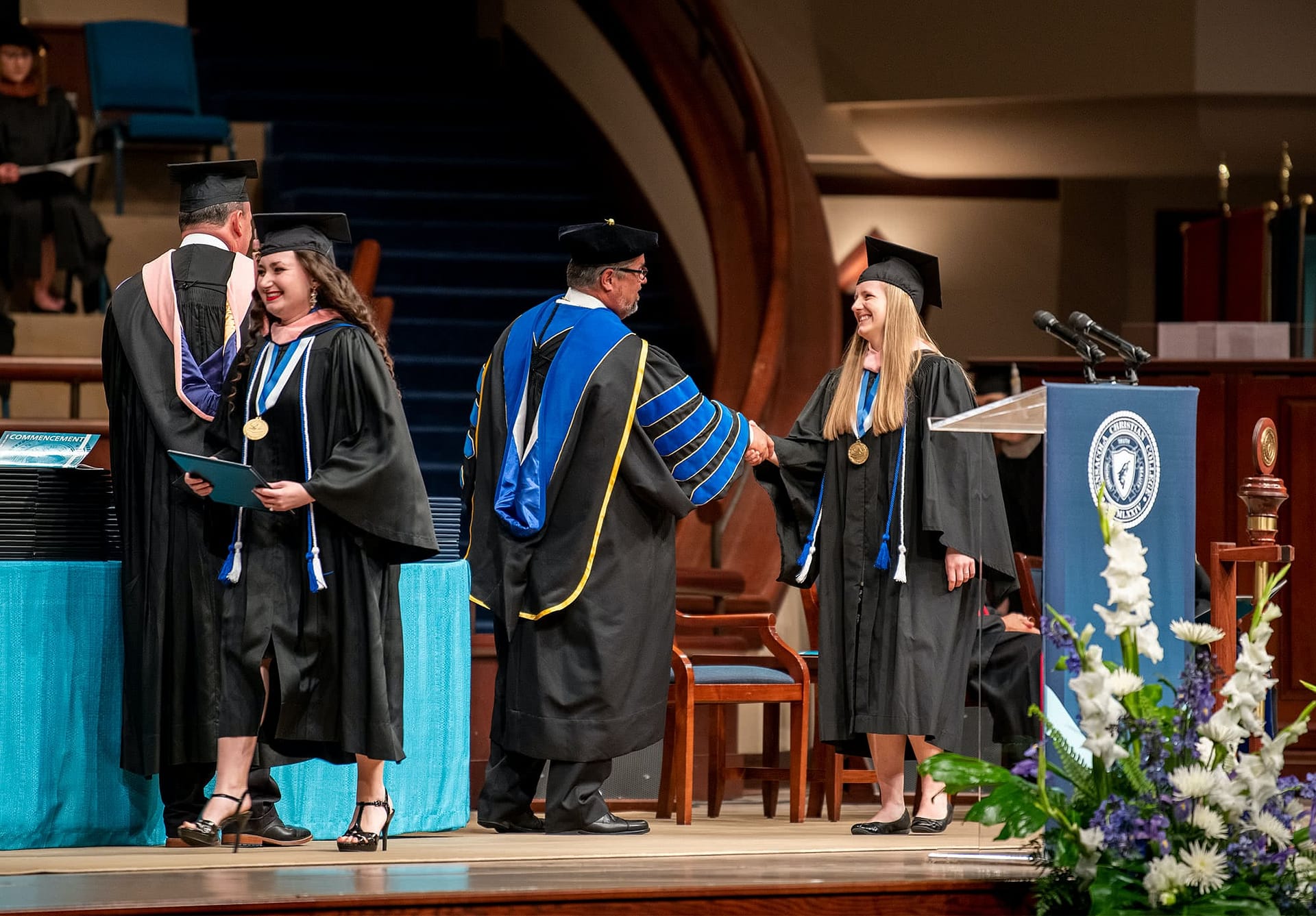 Dr. Shoemaker shaking hands with graduate walking across Crowne Centre stage