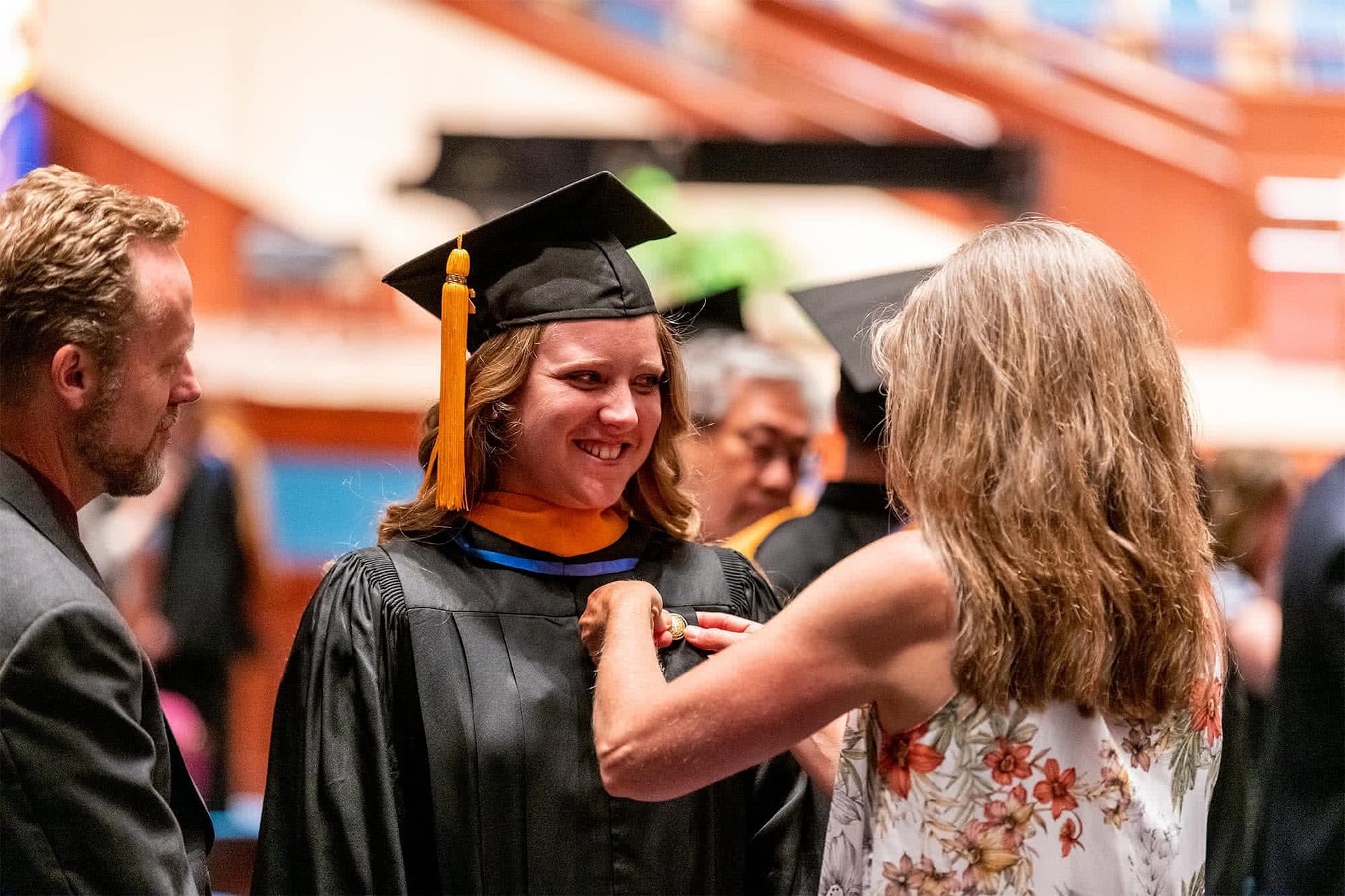 Female family member pinning a female nursing graduate