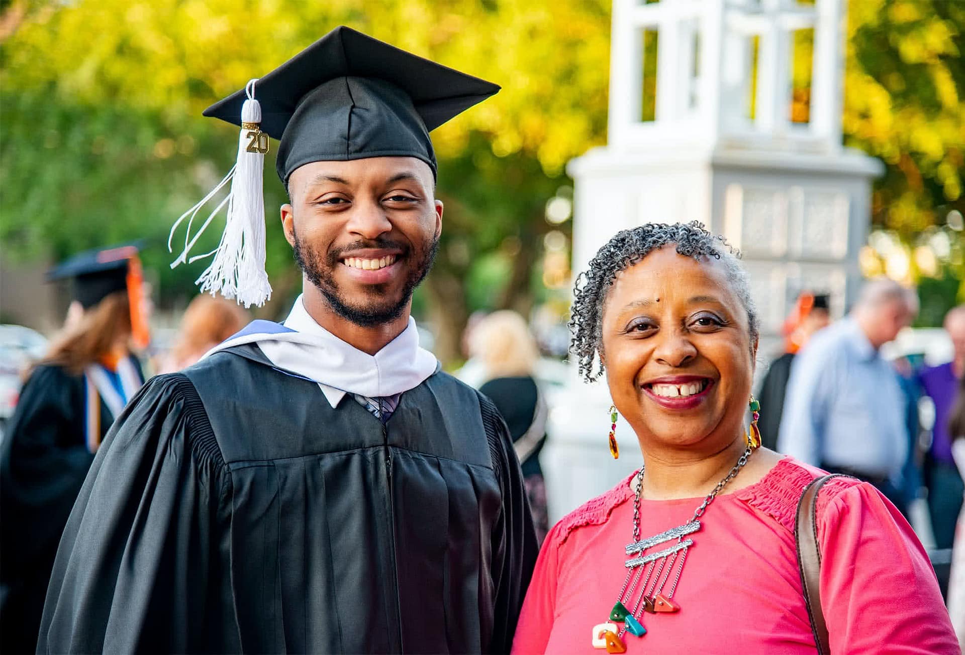 Male graduate standing beside mother.