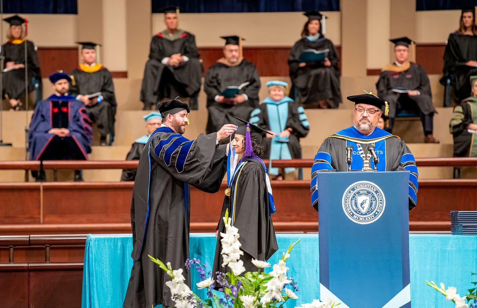 Female graduate receives medal on Crowne Centre stage.