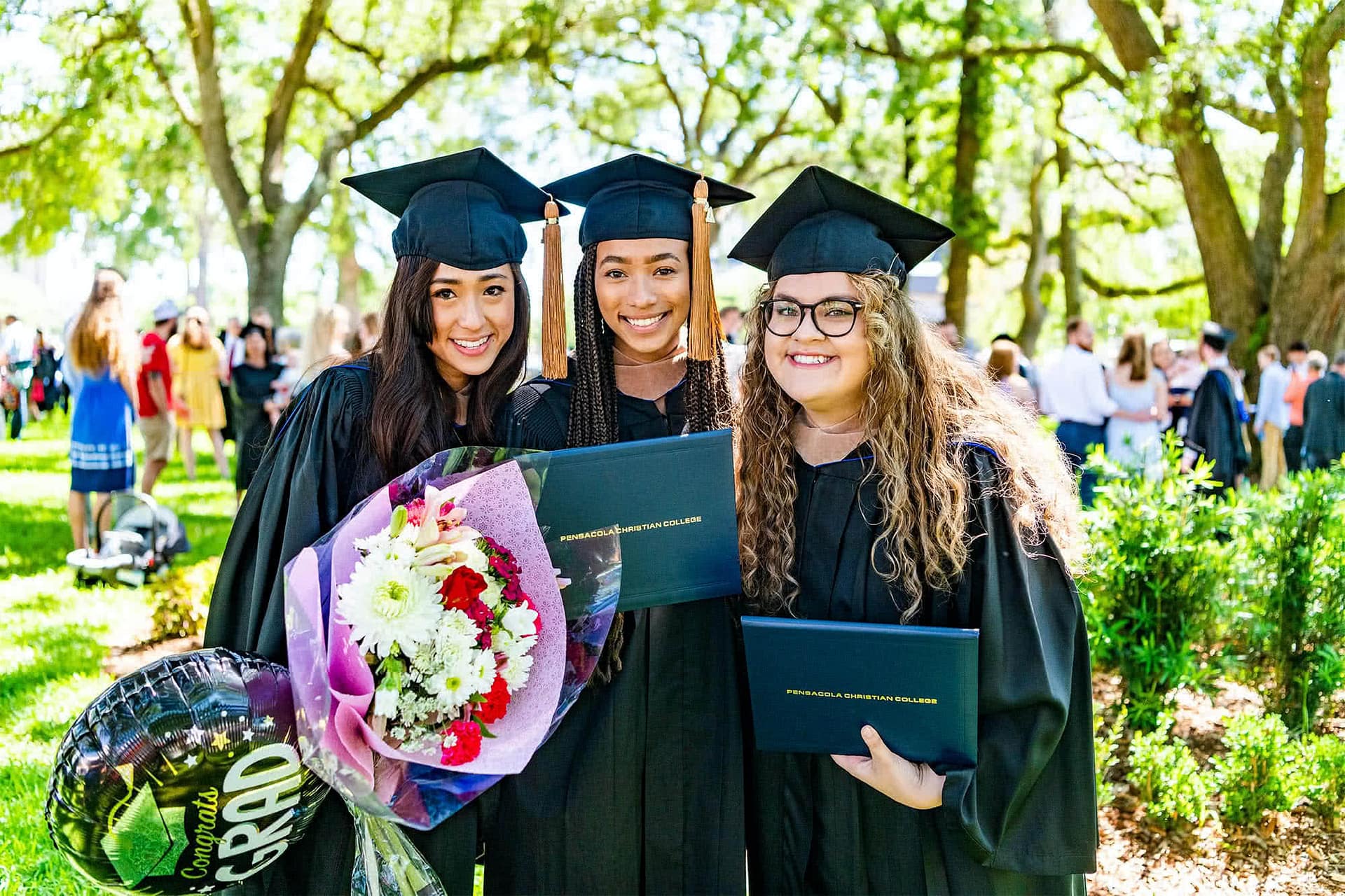 Three graduates in regalia pose for a photo.